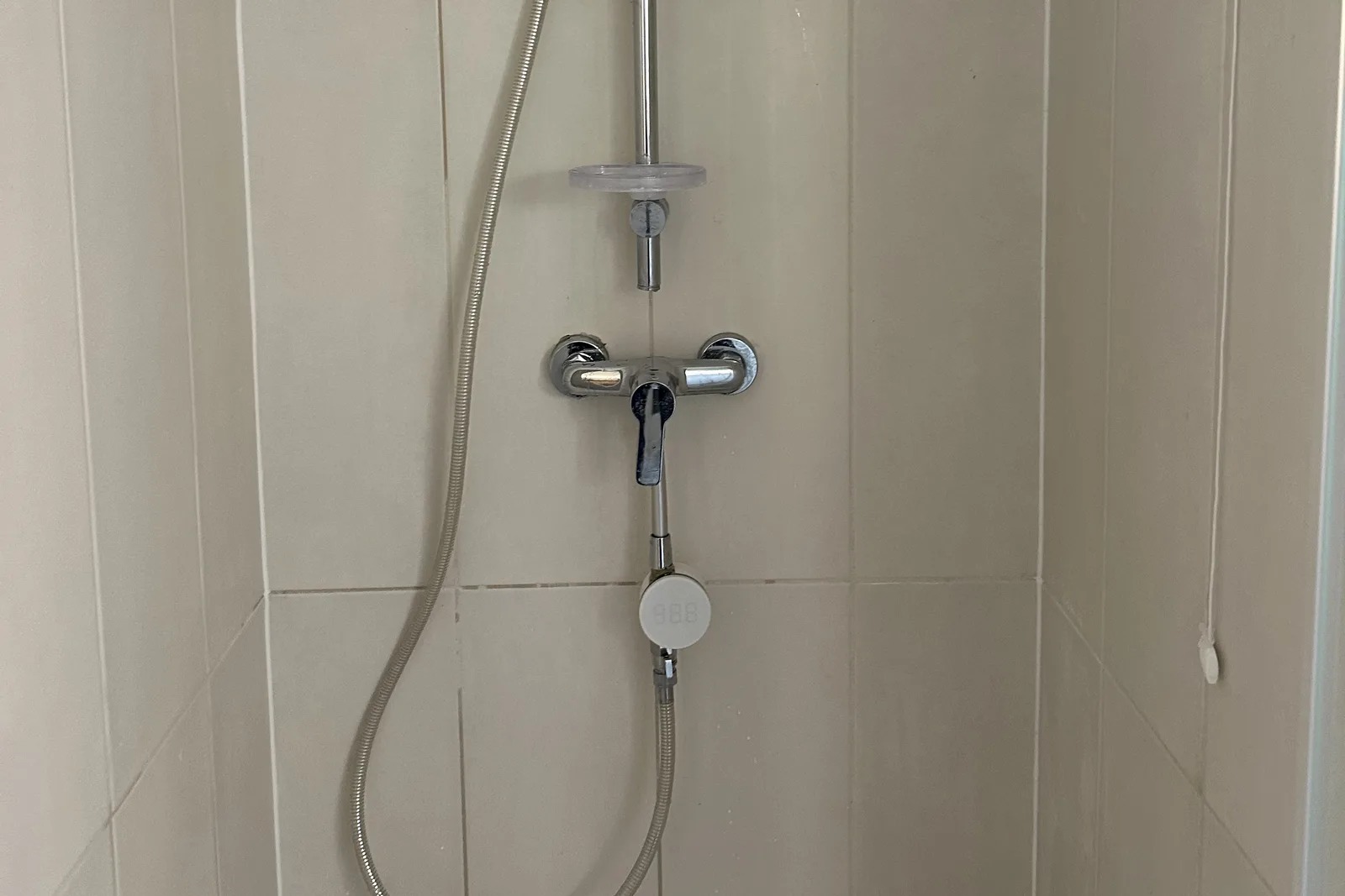 Molleaumètre vissé entre le mitigeur et le flexible d'une douche : un compteur d'eau connecté installé sans travaux
