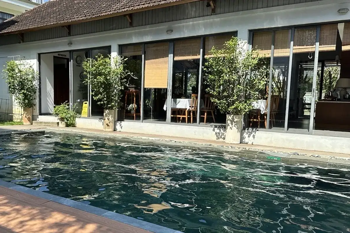 Piscine et restaurant vitré d'un petit hôtel entouré de végétation : l'hôtellerie durable commence par l'eau