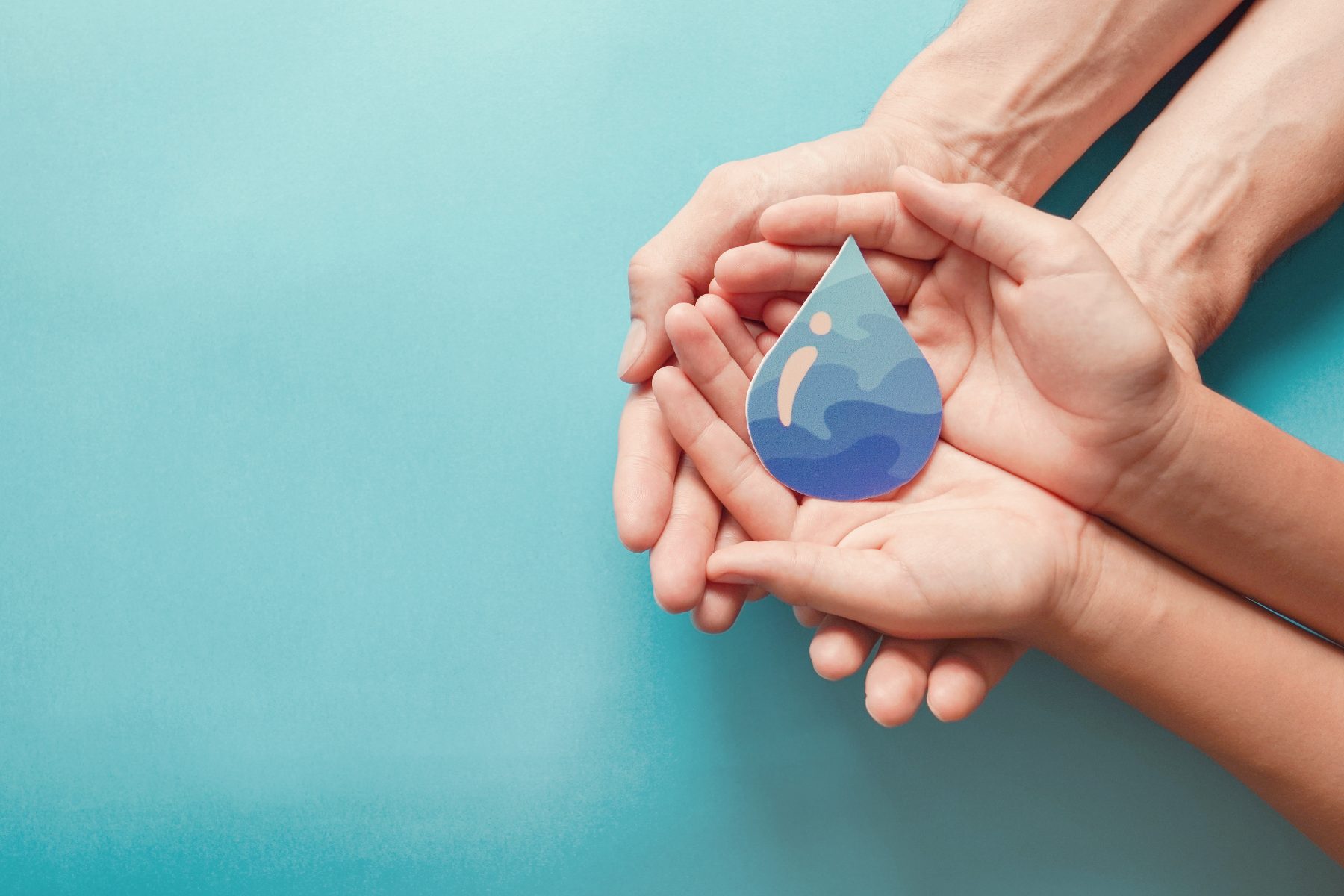 Hands holding a drop of water, a symbol of sustainable water management in hospitality