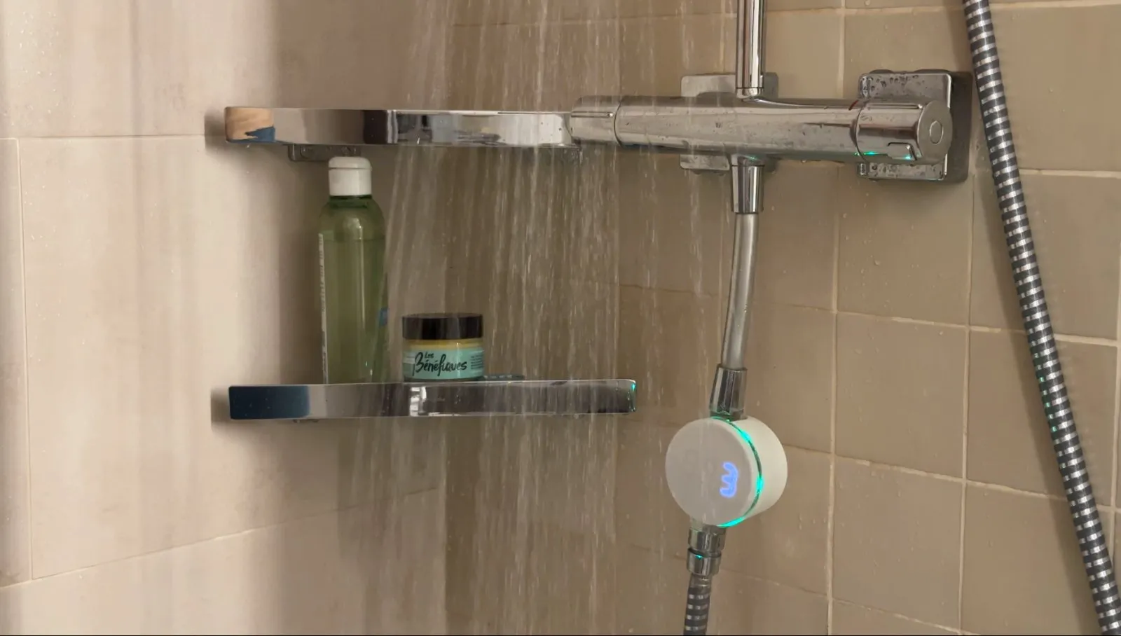 Molleaumètre installé sur le flexible d'une douche, l'écran affiche le nombre de litres consommés