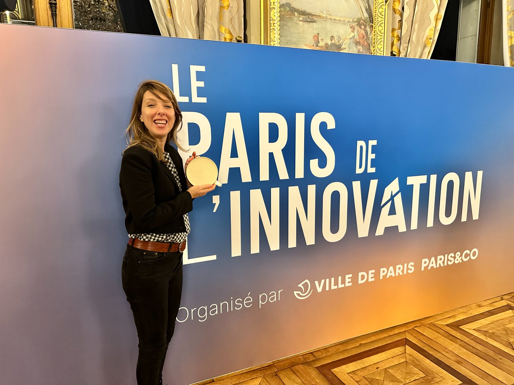 La fondatrice de Molleau, trophée en main, devant le mur « Le Paris de l'innovation » organisé par la Ville de Paris et Paris & Co
